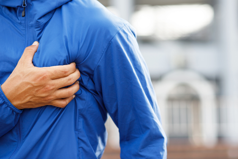 Man clutching his chest, showing signs of discomfort as regards to a potential heart disease
